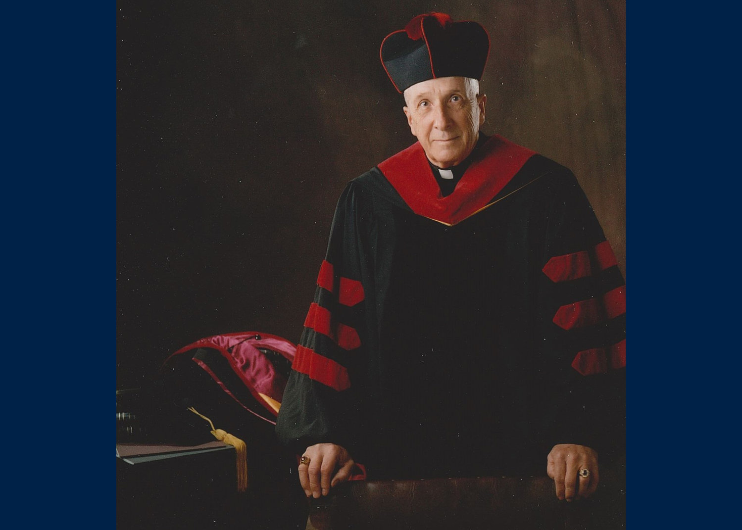 Father George Kramer is photographed while wearing his roman collar and doctoral academic garb.
